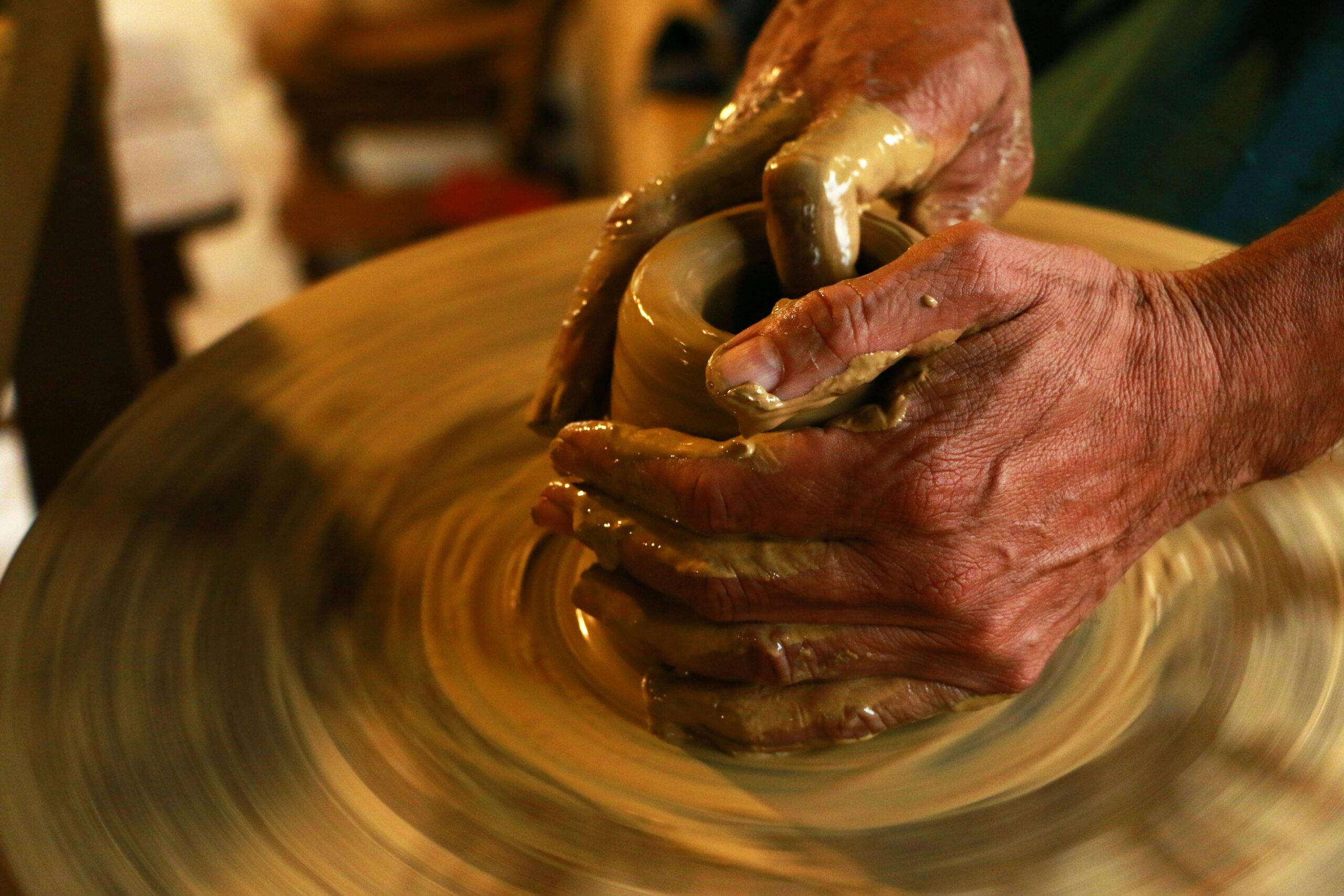 Close-up of hands shaping clay on a pottery wheel, highlighting the art of ceramics.